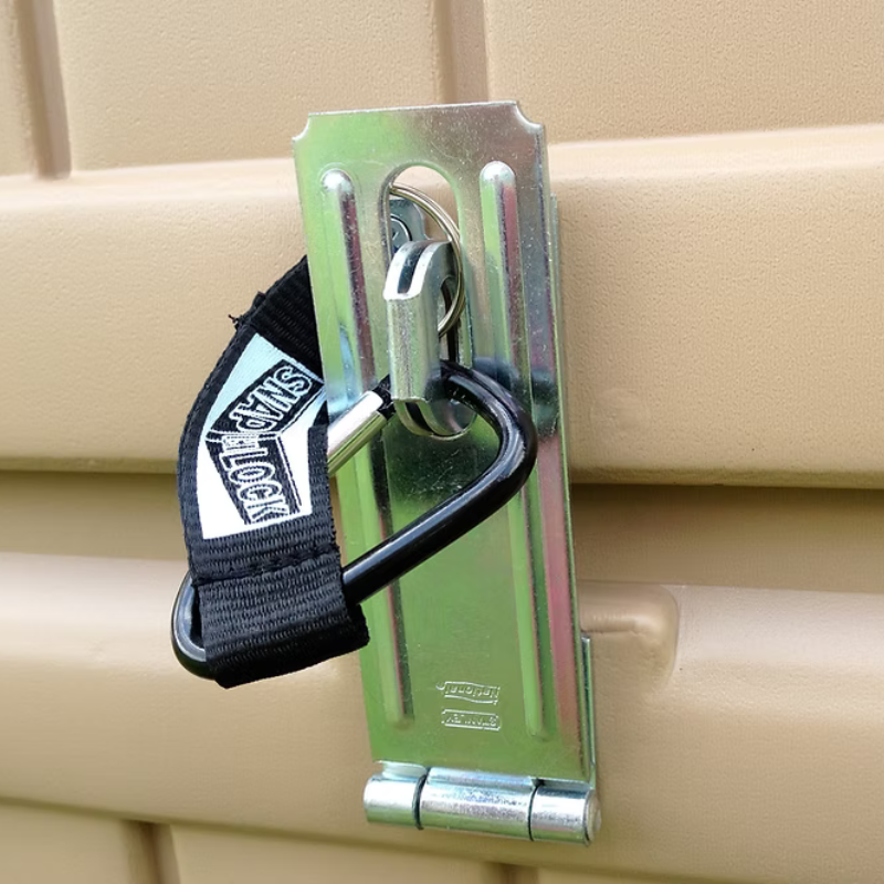 Metal clip with a strap attached to a beige surface, featuring a brand logo.