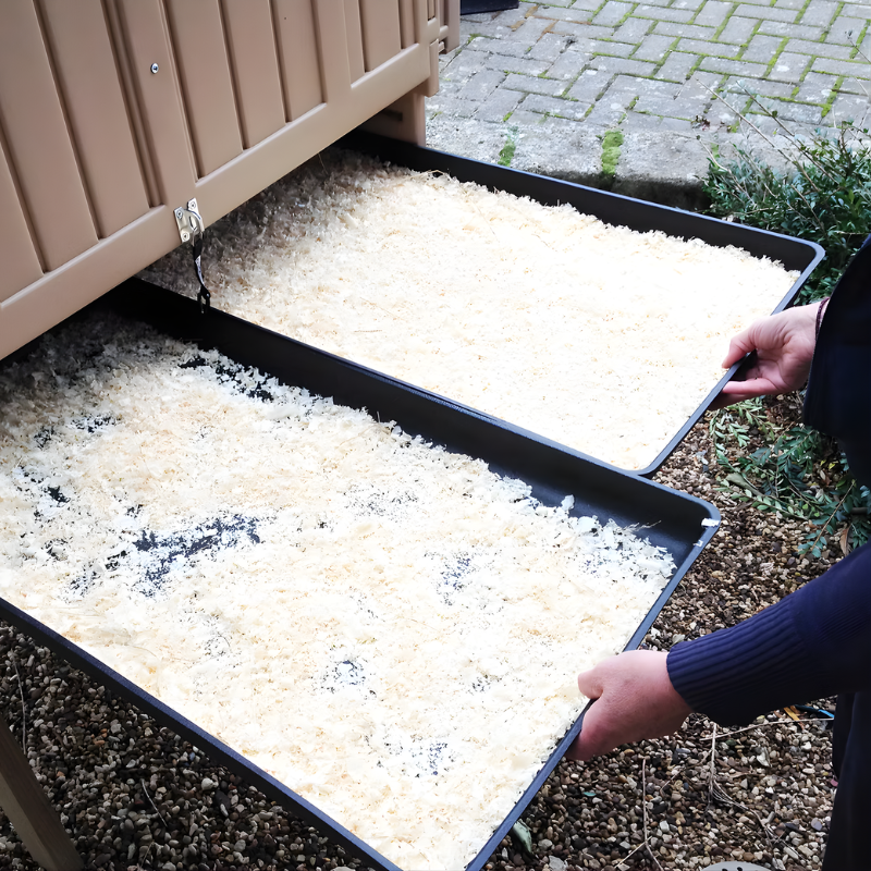 Person handling trays of beige plastic chicken coop.