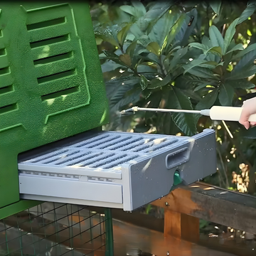 Person cleaning green plastic chicken coop