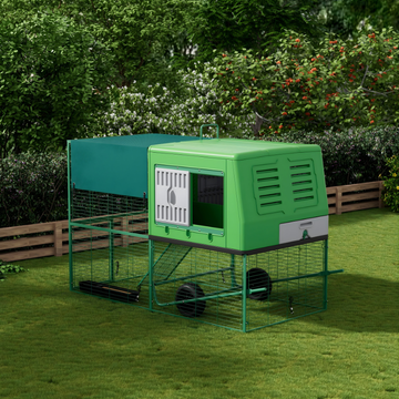 Green chicken coop with a run in a garden setting